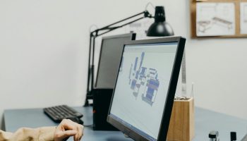A person working at a desk with a computer monitor in an organized office setting.